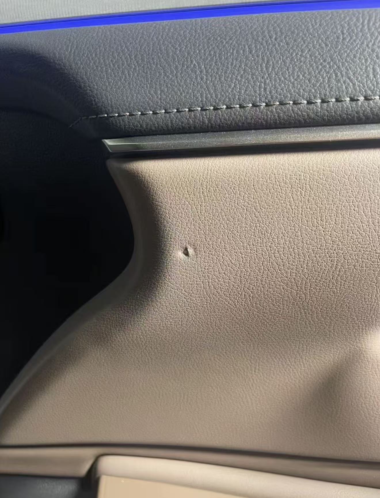 Car Door Interior Panel Repair — Before: A visible puncture in the brown door panel surface.