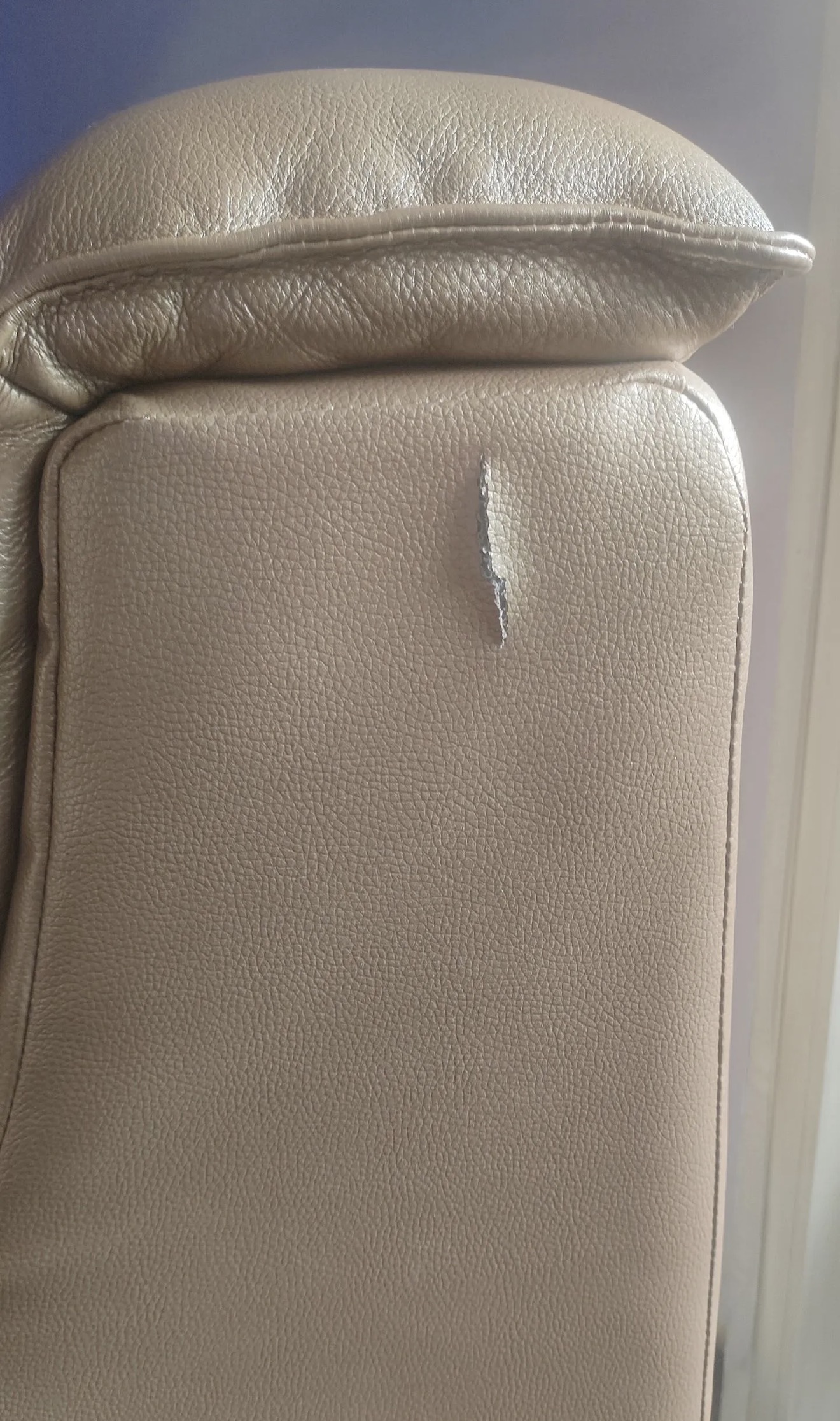 Beige Leather Sofa Scratch Repair — Before: A visible gouge in the beige leather sofa before repair.