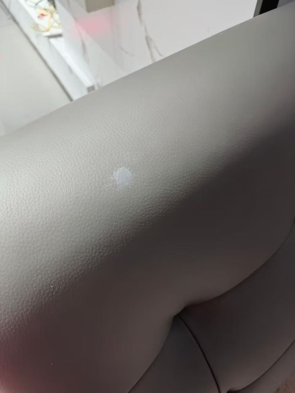 Grey Leather Sofa Surface Repair — Before: A worn patch on a grey leather sofa before repair.