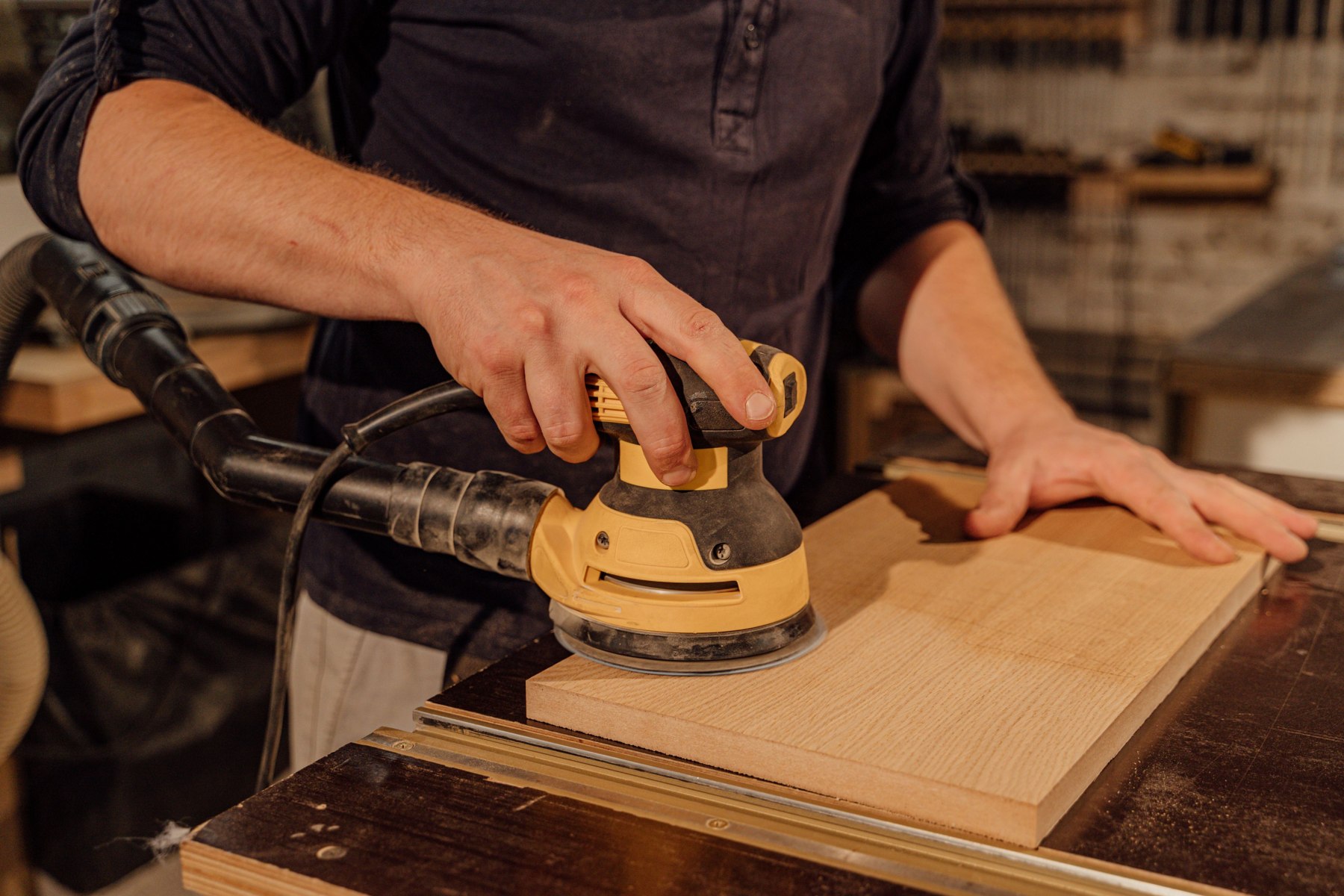 Close-up of a craftsperson sanding a wooden panel — illustrative stock photo