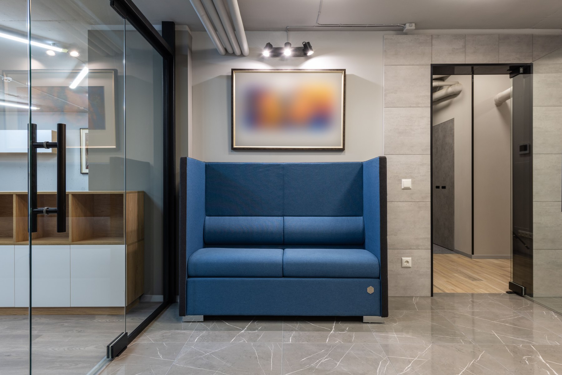 Office lounge with tiled flooring, glass doors and upholstered seating — illustrative stock photo